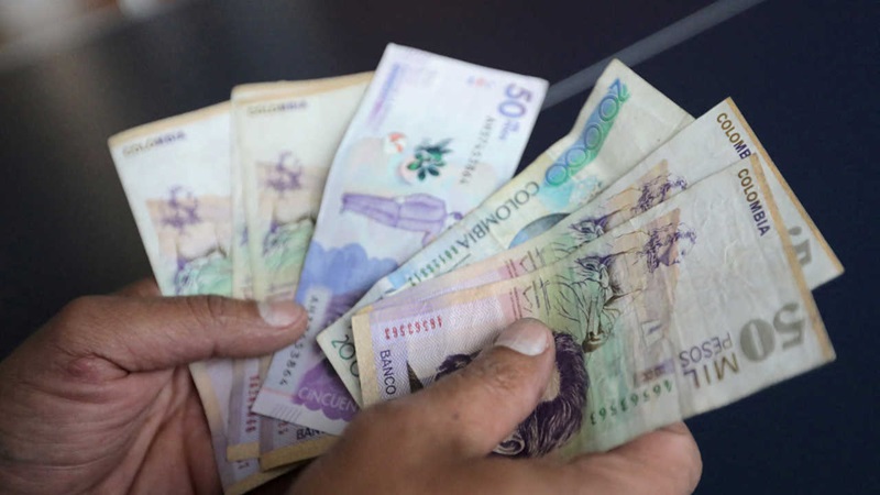 Pessoa segurando os pesos colombianos em espécie
